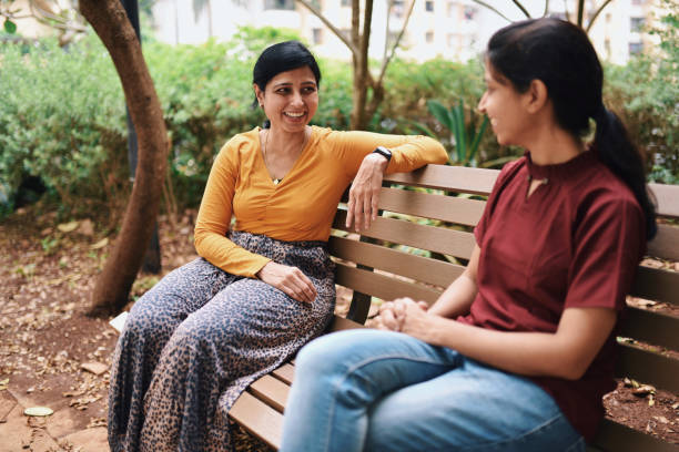 istock Happy looking sisters discussing while sitting on a bench in public park 1279793538