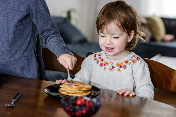 istock Girl spreading maple syrup on sister's pancakes 1279793795