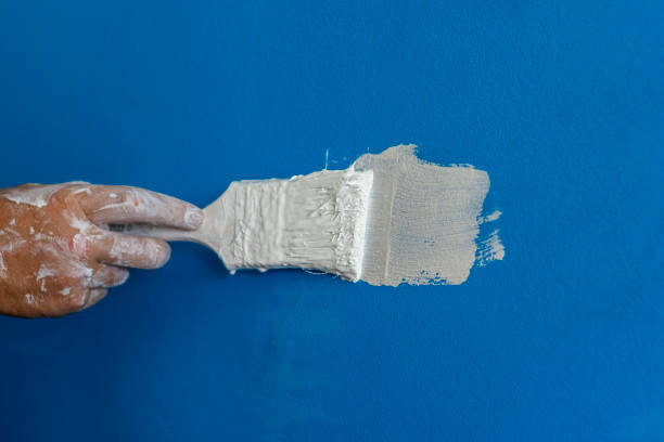istock Young man painting with a paintbrush over a blue wall at home. 1279794647