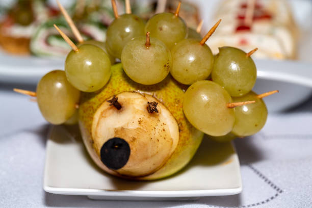 Fruit dessert. Hedgehog made of pears and grapes