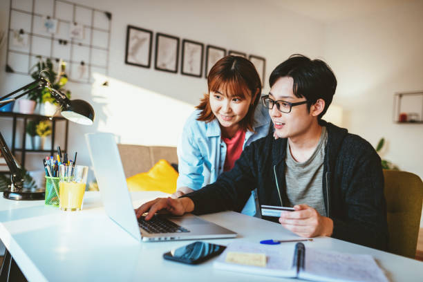 istock Asian couple at home, using internet to order goods, paying with credit card 1279797449