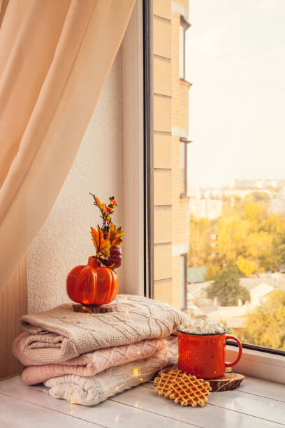 istock Cozy autumn still life on the windowsill: warm wool sweaters, pumpkins, maple leaves and a Cup of cocoa with marshmallows and waffles 1279798064