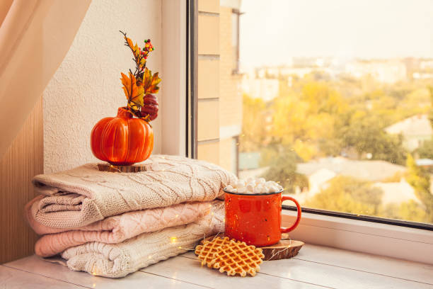 istock Cozy autumn still life on the windowsill: warm wool sweaters, pumpkins, maple leaves and a Cup of cocoa with marshmallows and waffles 1279798071