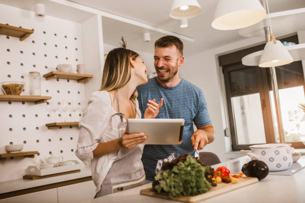 istock Young couple cooking together in kitchen reading recipes on digital tablet. 1279798837