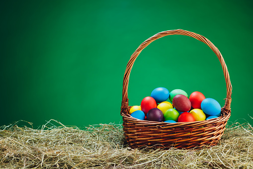 Easter color eggs in festive gift basket, blue background, close-up view
