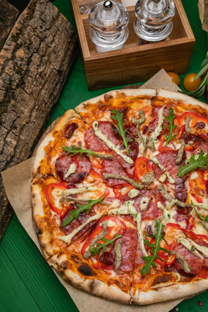 Pizza with cheese and ham, salami, greens, sausage