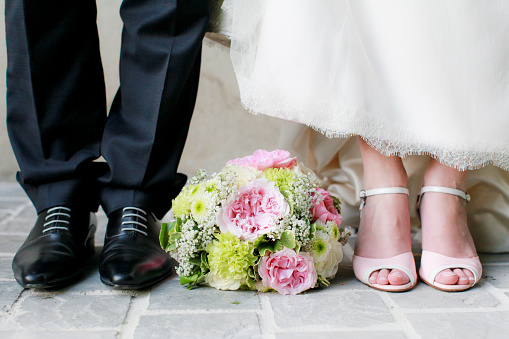 Photo of the groom's feet with the bouquet of flowers in the middle