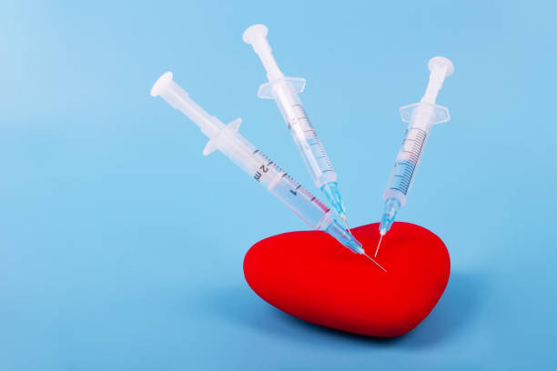istock Red heart and a syringe on blue background 1279805097
