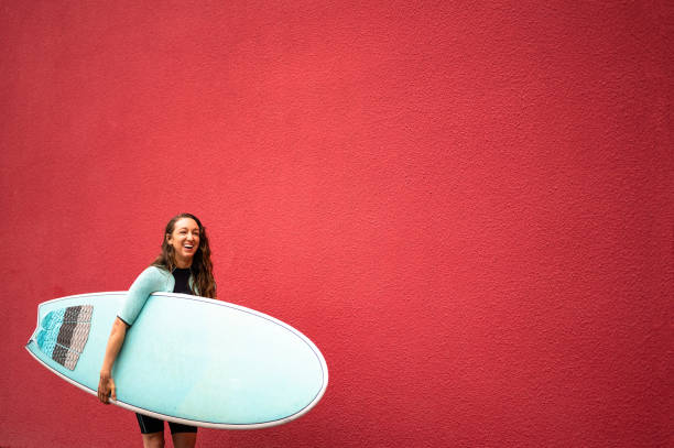 istock Female surfer against a red background 1279805141