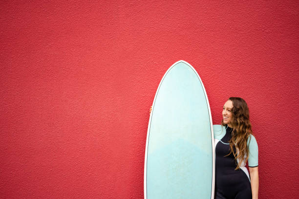 istock Female surfer against a red background 1279805239