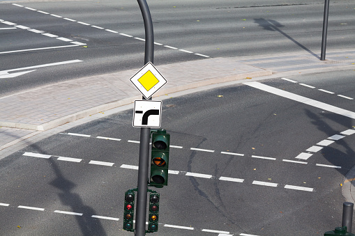 Selective focus shot of a Priority Road  Sign on a metal pole with a traffic light beneath it