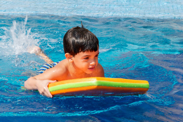 istock 6 year old boy playing in pool with bodyboard. 1279808142