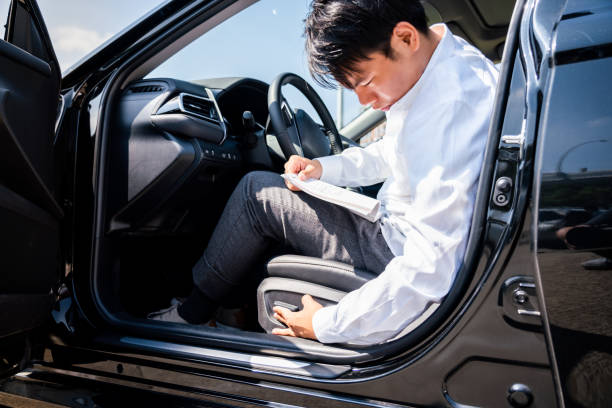 jovem lendo livro de instruções e ajustando seu assento em carro novo - adult manual worker automobile industry transportation - fotografias e filmes do acervo