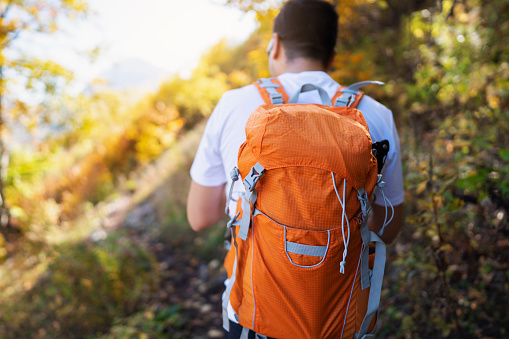 Close-up of a Caucasian man with a backpack hiking in the forest on an autumn day.
