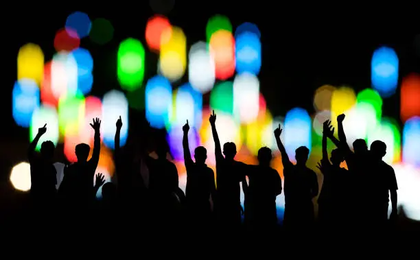 Photo of Siluette, a group of people raised their hands with bokeh.
