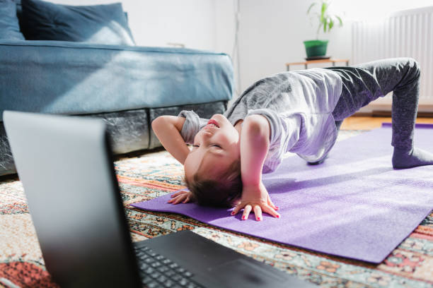 istock Little girl exercising at home using laptop 1279813025