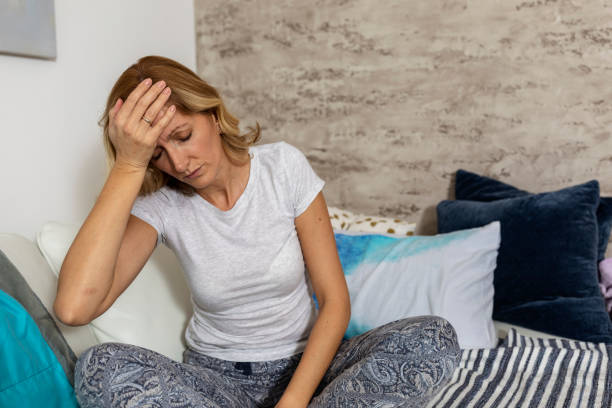 istock Woman sitting on a couch, holding her head, having a strong headache. 1279813113