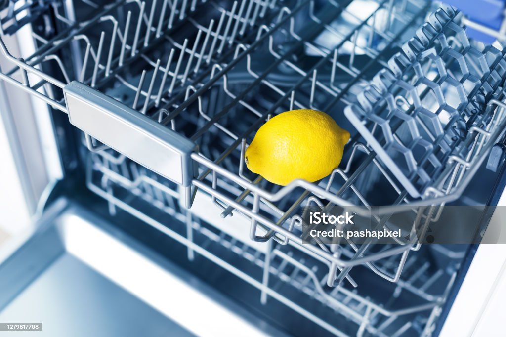 Home appliance dishwashing machine in kitchen interior, no people Empty dishwasher with fresh yellow lemon on shelf, aroma freshness care concept, clean equipment,  home appliance dishwashing machine in kitchen interior, no people Dishwasher Stock Photo