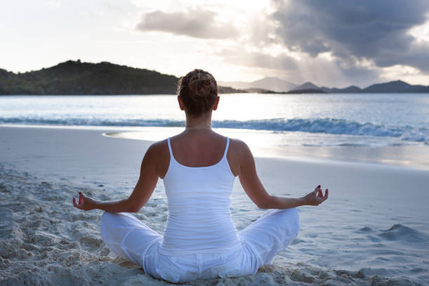 istock woman doing yoga meditation on a tropical beach 1279817921