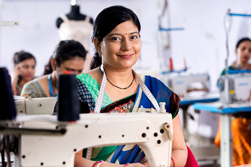 Indian woman textile worker using sewing machine on production line