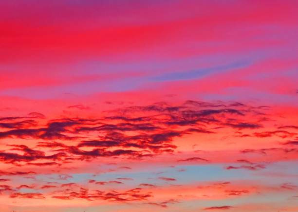 A stunning sunset scene featuring a vivid and colorful horizon, with dramatic clouds dispersed across a glowing sky