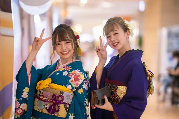 Portrait of young women in ‘Furisode’ kimono showing a peace sign on ‘Seijin Shiki’ coming-of-age ceremony day