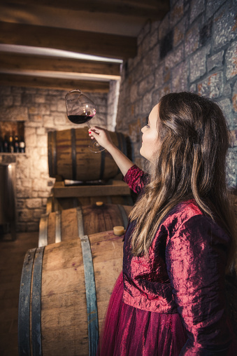 Woman tasting a glass of red wine in the wine cellar