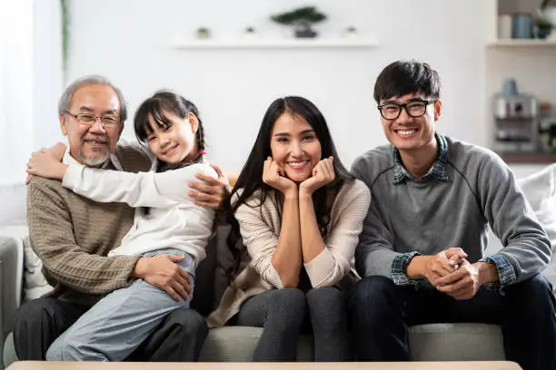 Group Portrait of Happy multigenerational asian family sit on sofa couch in living room with smile. Muti genration family happiness concept.