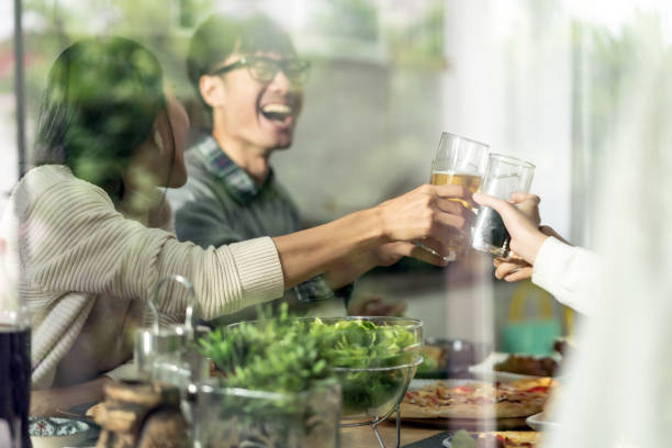 alegres aplausos familiares asiáticos multigeneracionales juntos - los niños y los padres brindis bebidas mientras almuerza fotografías e imágenes de stock