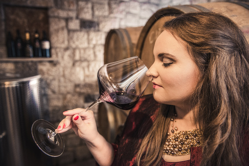 Woman smelling a glass of red wine in the wine cellar