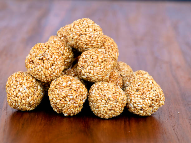 White sesame seed balls made with heated jiggery against wooden background White sesame seed balls made with heated jiggery, tasty and nutritious candy ,against wooden background dissert stock pictures, royalty-free photos & images