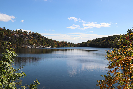 Photo with autumn colors on the trees with a beautiful lake, mountains, and sky in a New York state park - beautiful wide-angle view to highlight the entire lake