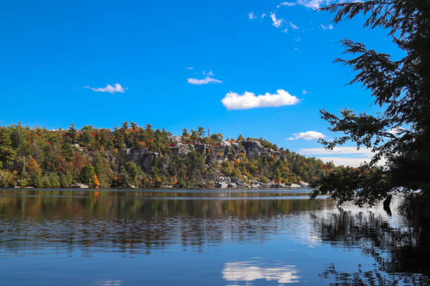 Beautiful Fall Colors at Lake Minnewaska in Upstate New York - view of the lake from water level Photo with autumn colors on the trees with a beautiful lake, mountains, and sky in a New York state park - photo taken at water level to highlight the lake orange county new york stock pictures, royalty-free photos & images