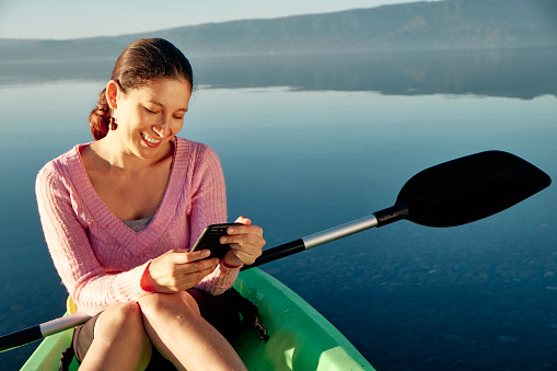 Woman sitting in a kayak smiling in a video called . In the background the blue lake. Copy space.