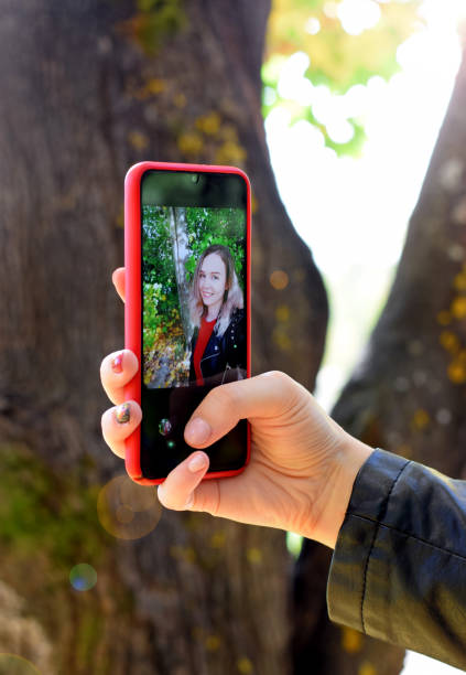 istock Young woman making selfie with a smartphone through front camera outside 1279831790