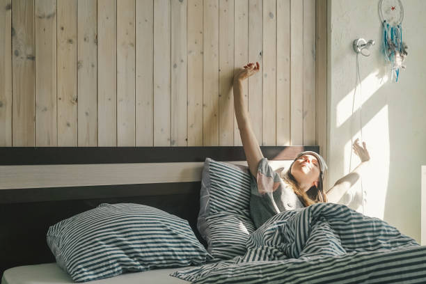 istock A young woman stretches in bed. Waking up. 1279832529
