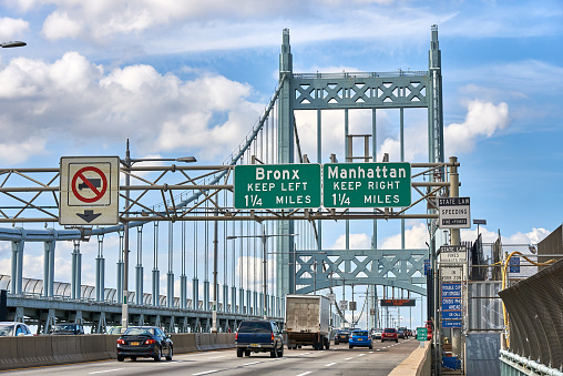New York, NY - September 12 2020: Cars and trucks on the suspension bridge over Hell Gate, part of Robert F Kennedy Bridge. Signs indicate exits to the Bronx and Manhattan. The RFK Bridge was formerly know as the Triboro bridge and it joins Manhattan, Bronx and Queens.