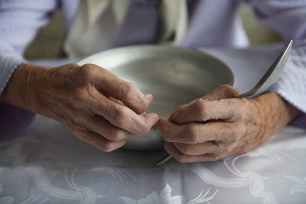 veja de cima. as mãos de uma velha avó de 90 anos estão segurando uma tigela de alumínio vazia e colher, pobreza e pobreza, a fome da geração mais velha. - esfomeado - fotografias e filmes do acervo