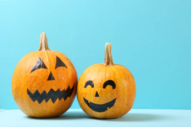 istock pumpkins with painted faces on a colored background for Halloween. 1279838273