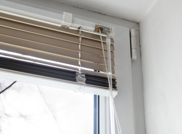 istock Stuck blinds.Adjusting the white blinds in height use a cord.Half-open metal blinds mounted on a plastic window. 1279838293