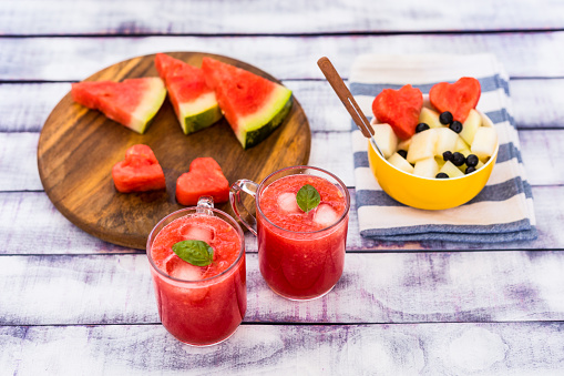 Fruit dessert, watermelon, melon, banana and chokeberry, with iced watermelon juice in glass, close up