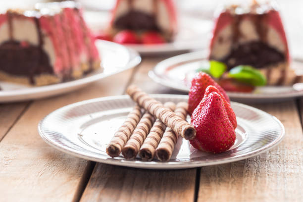 ice cream cake slices on plate with sweet rolls and strawberries in foreground, selective focus, close-up, no people