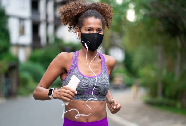 istock Afro woman jogging and wearing protective face mask 1279842771