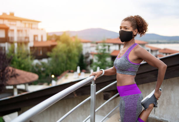istock Afro woman stretching and wearing protective face mask 1279842783