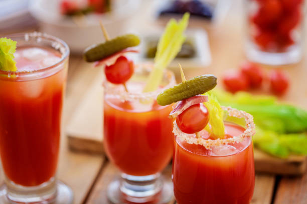 Delicious red tomato Bloody Mary cocktail in the decorative glass with olives and tubule standing on the bar counter