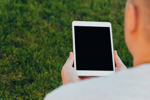 istock male hands holding an electronic tablet mock-up for your text message or information content, against the background of green nature 1279843080