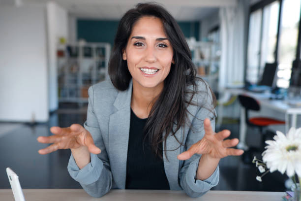 mulher de negócios confiante olhando e falando através da webcam enquanto faz uma videoconferência do escritório. - gesturing business looking at camera caucasian - fotografias e filmes do acervo