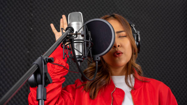 istock young attractive Asian woman musician singer in recoding studio with microphone. Performance arts concept. 1279844230
