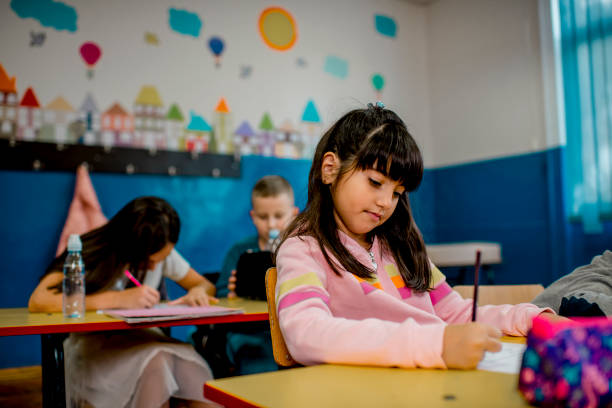 istock Elementary schoolchildren writing at the desk in the classroom. 1279844603