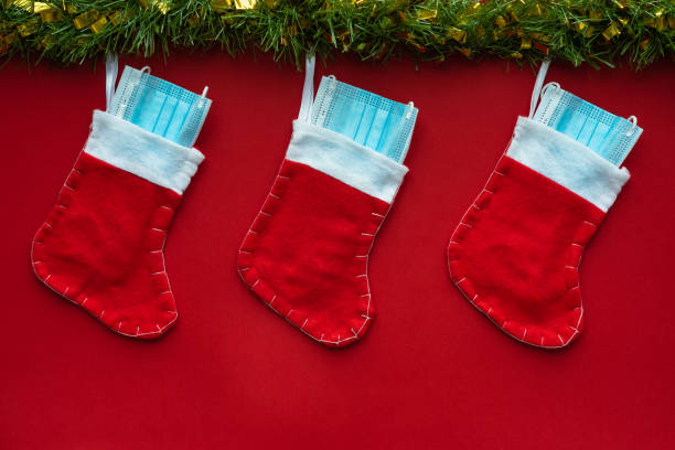 Christmas decoration with Coronavirus on a red background, christmas socks, face masks and hydroalcoholic gels. Covid concept on christmas.